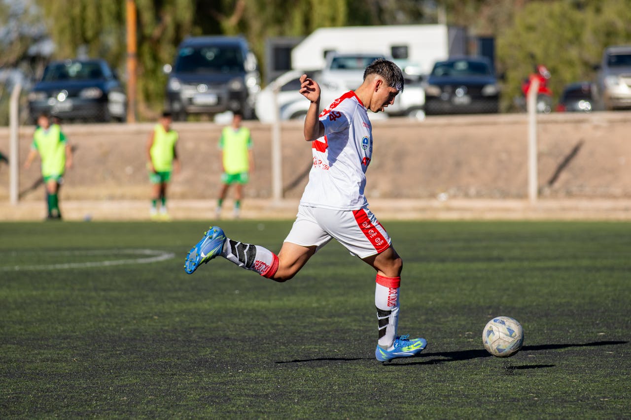 services-01 Young soccer player takes an athletic kick on an outdoor field during a match.
