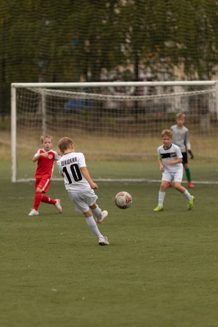 services-03 Young boys playing soccer on an outdoor field during the day. Action shot with goalpost.