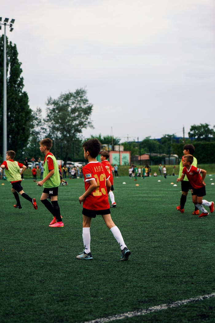 about-01 Young kids playing soccer on a green field during the day. Engaged in a fun sporting activity.