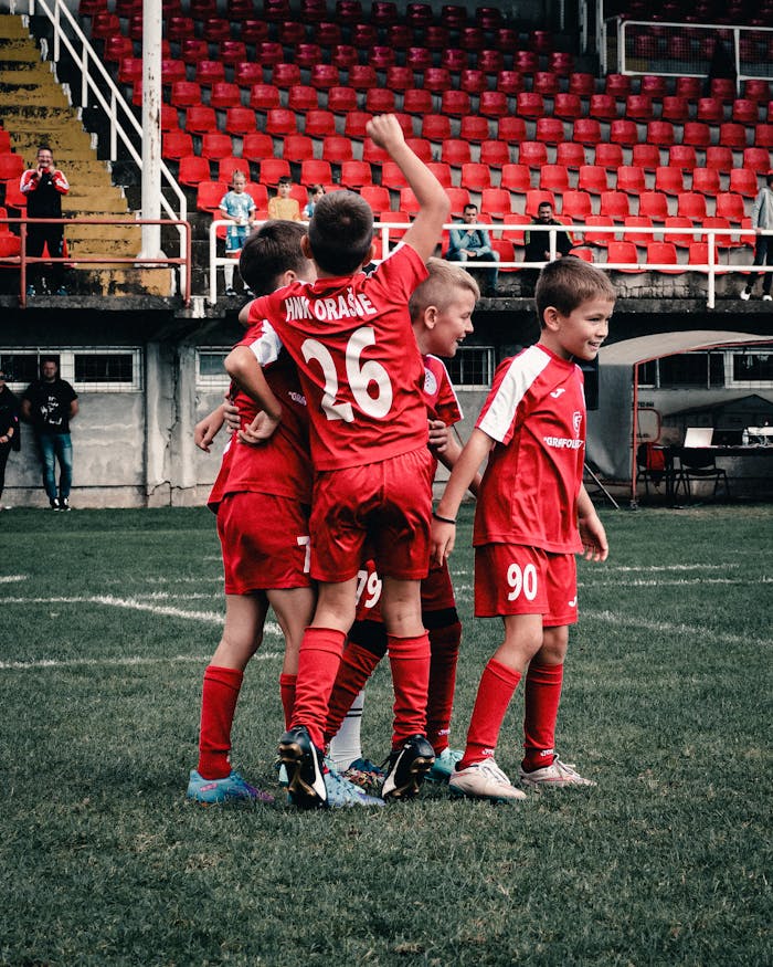 gallery-2 A group of young boys celebrating a success during a football game on a grassy field in Orašje.