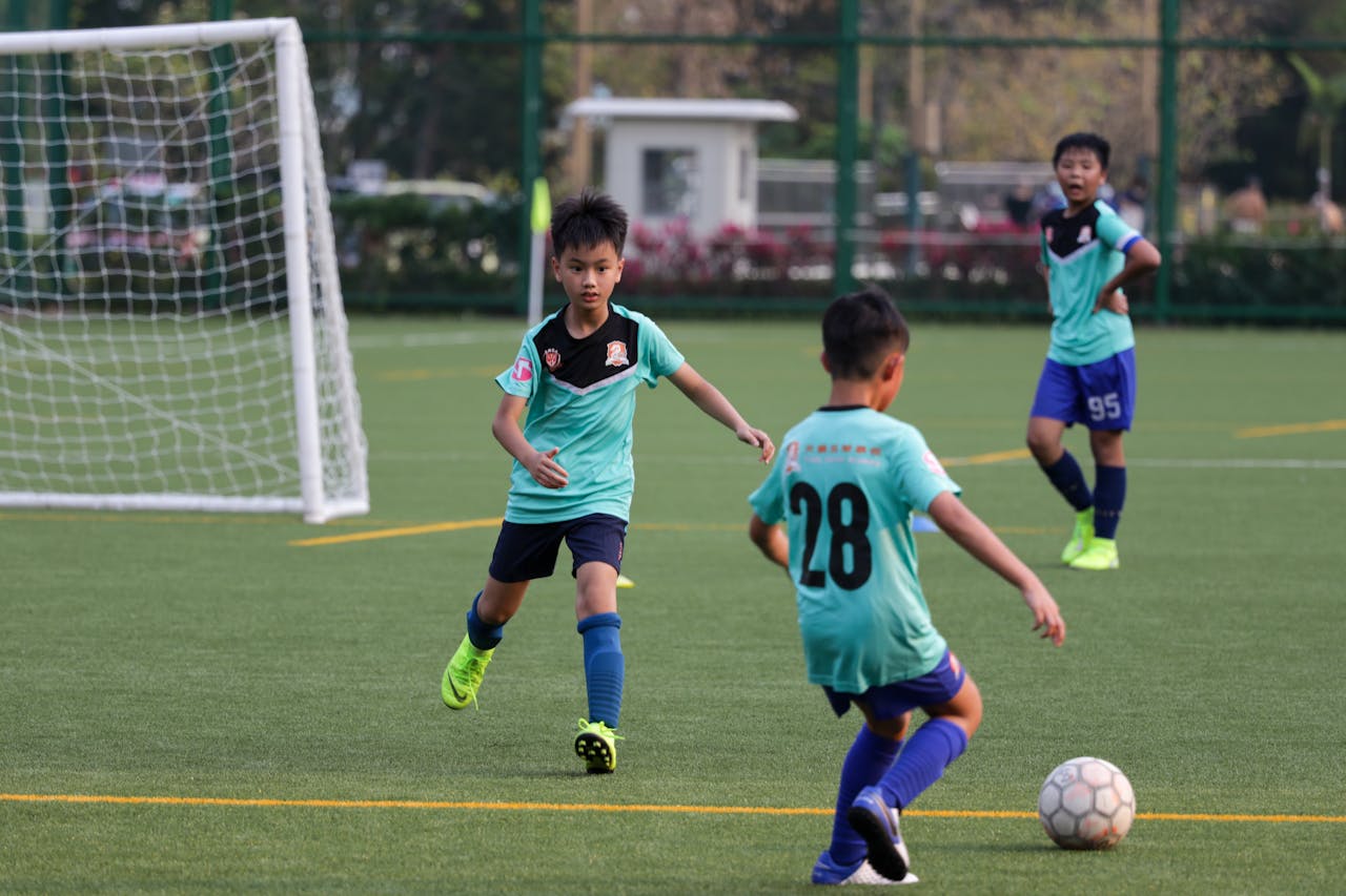 services-img Boys playing youth soccer on a sunny day, wearing uniforms on a green field.