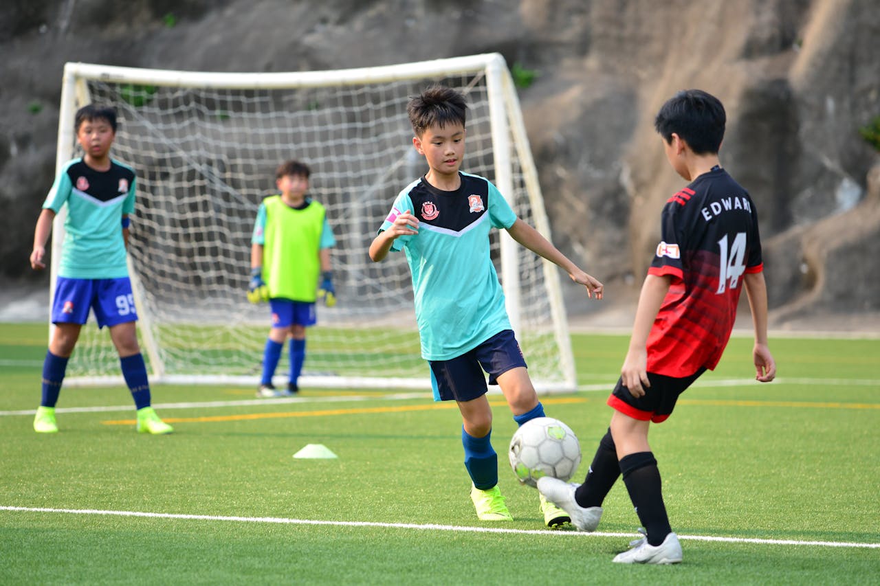hero-img-01 Boys playing soccer during a team training session outdoors on a sunny day.
